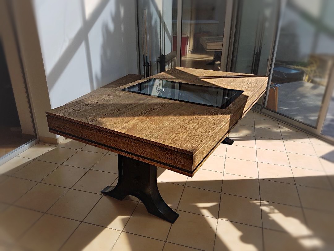 Le plateau en 3 parties de cette table ATELIER transformable en billard est constitué d'un centre en verre encadré de bois finition chêne brossé huilé. Le verre laisse apparaître le tapis gris ardoise du jeu de billard.